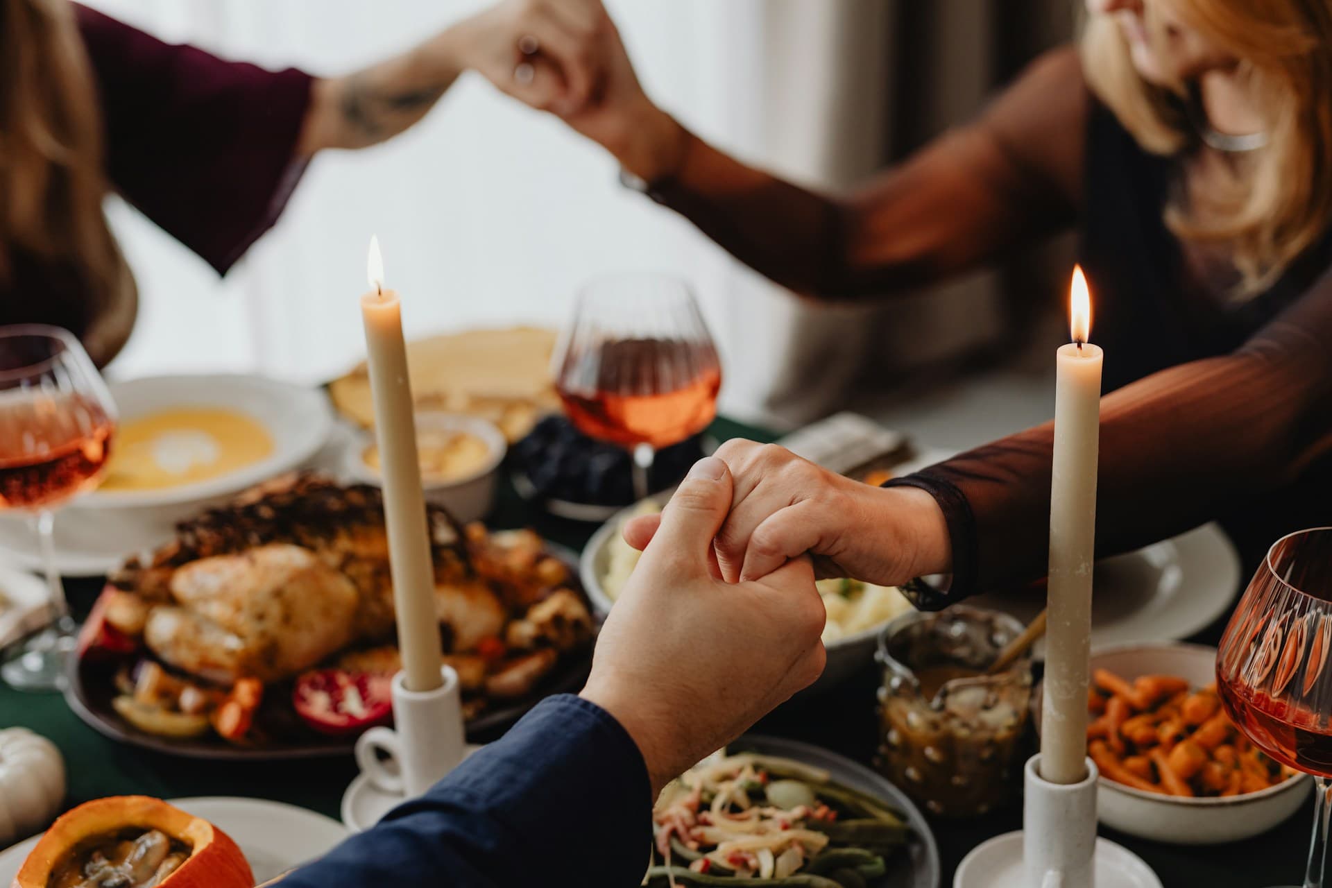 Family holding hands at Thanksgiving dinner.