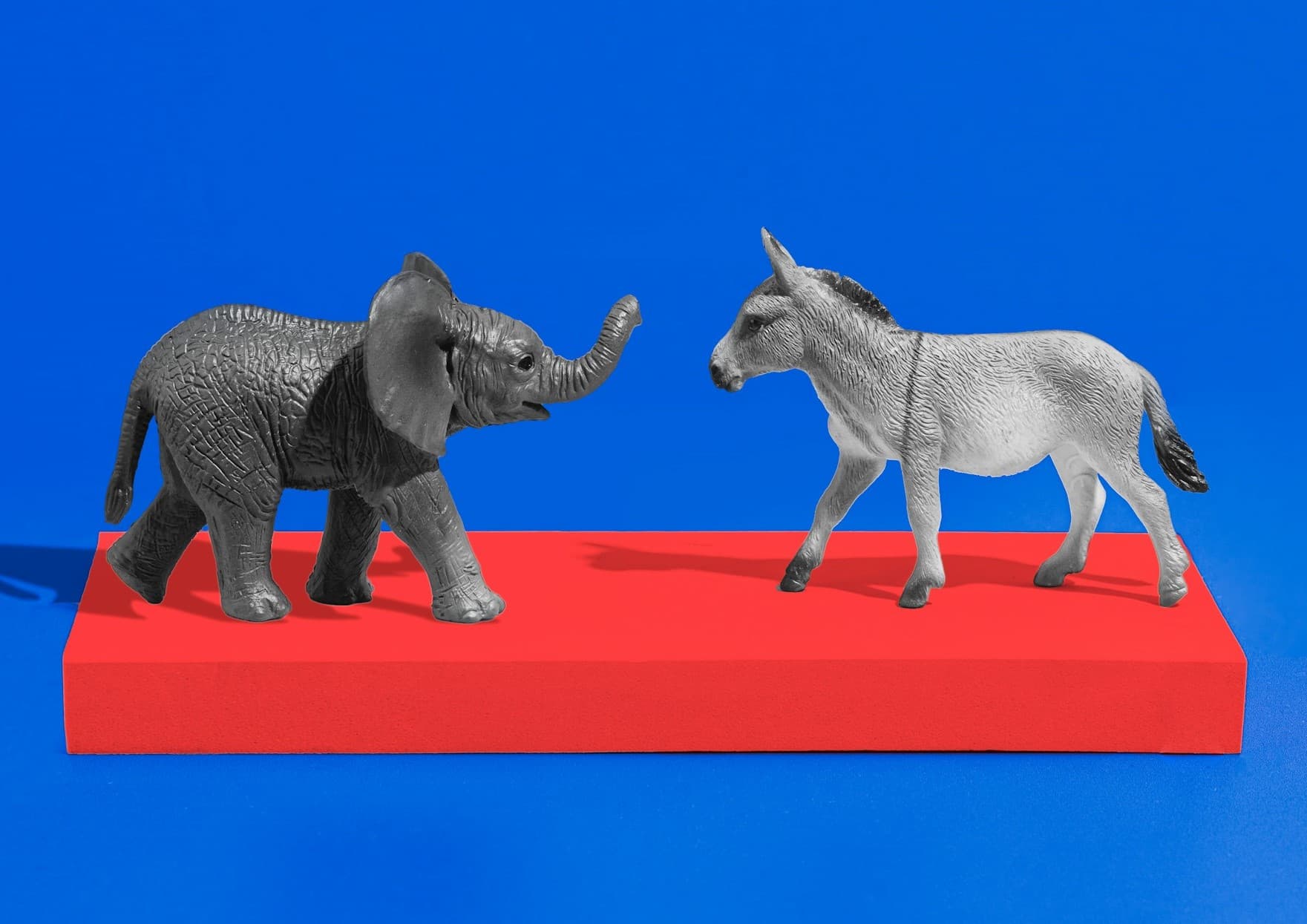 An elephant and donkey facing each other on a red bar. 