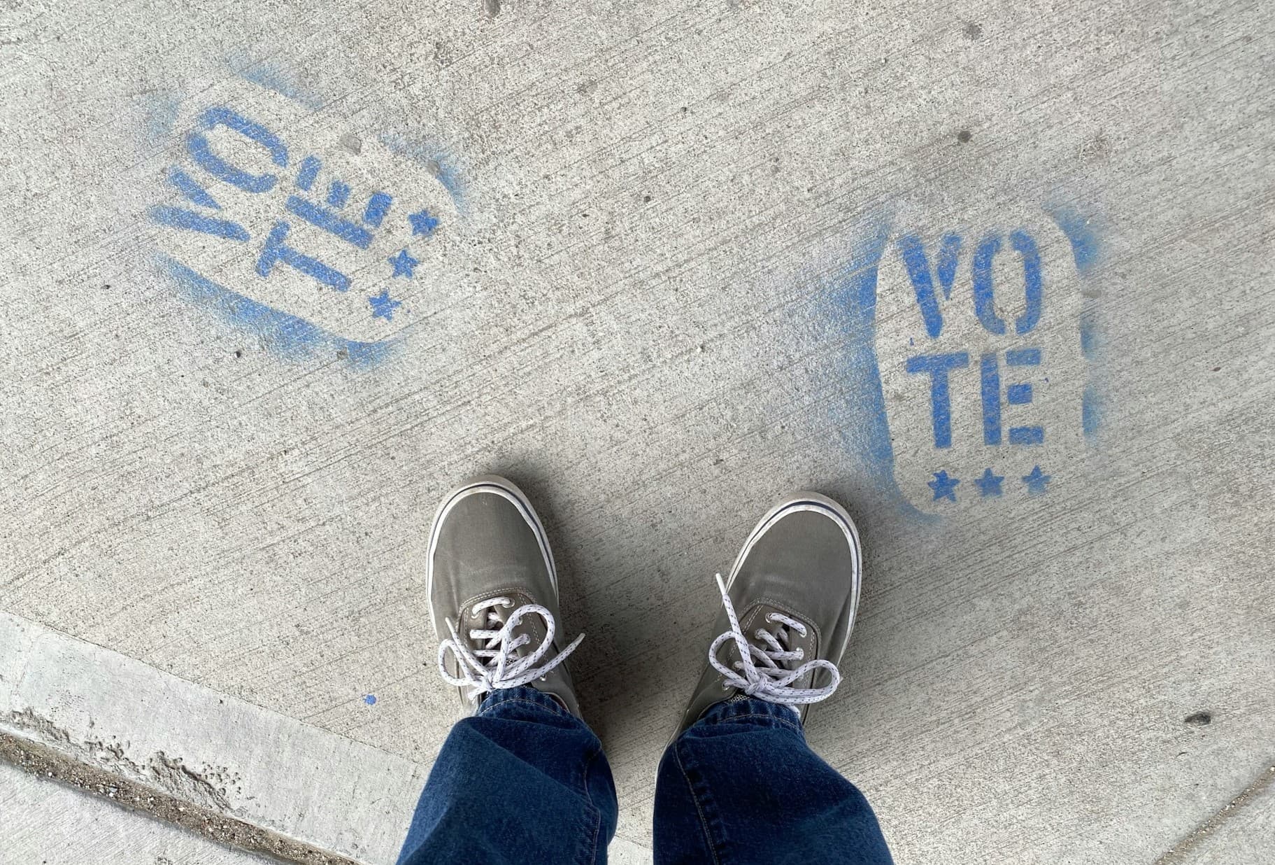 A pair of feet standing at two vote signs. 