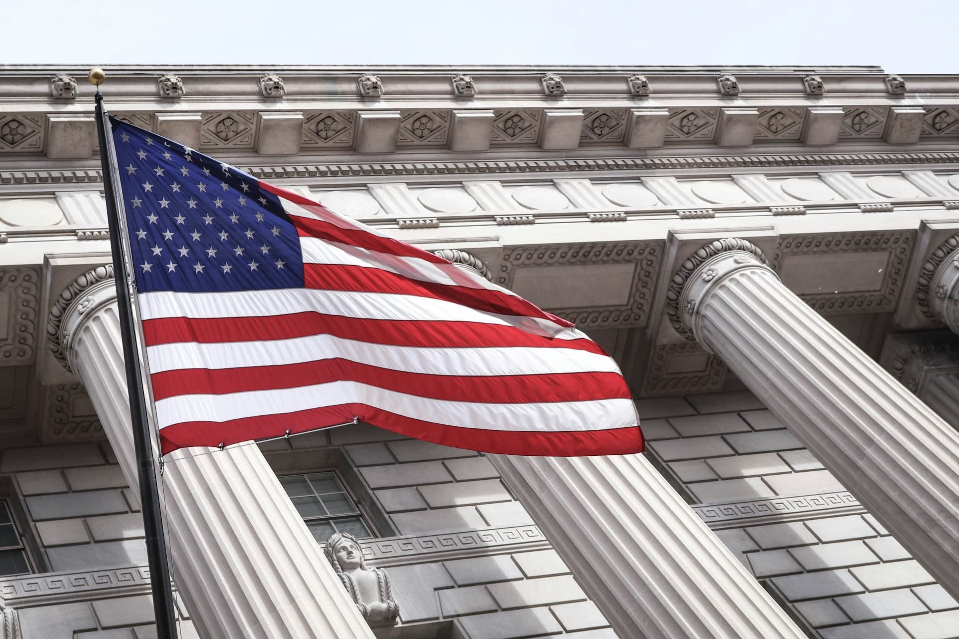 American flag in front of a government building with columns. 