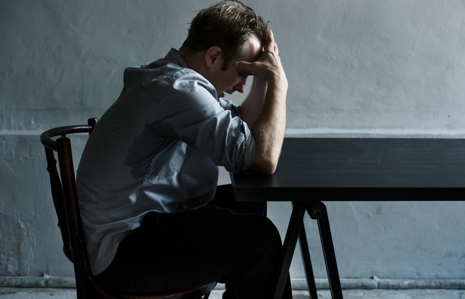 Man holding his head sitting at a table. 