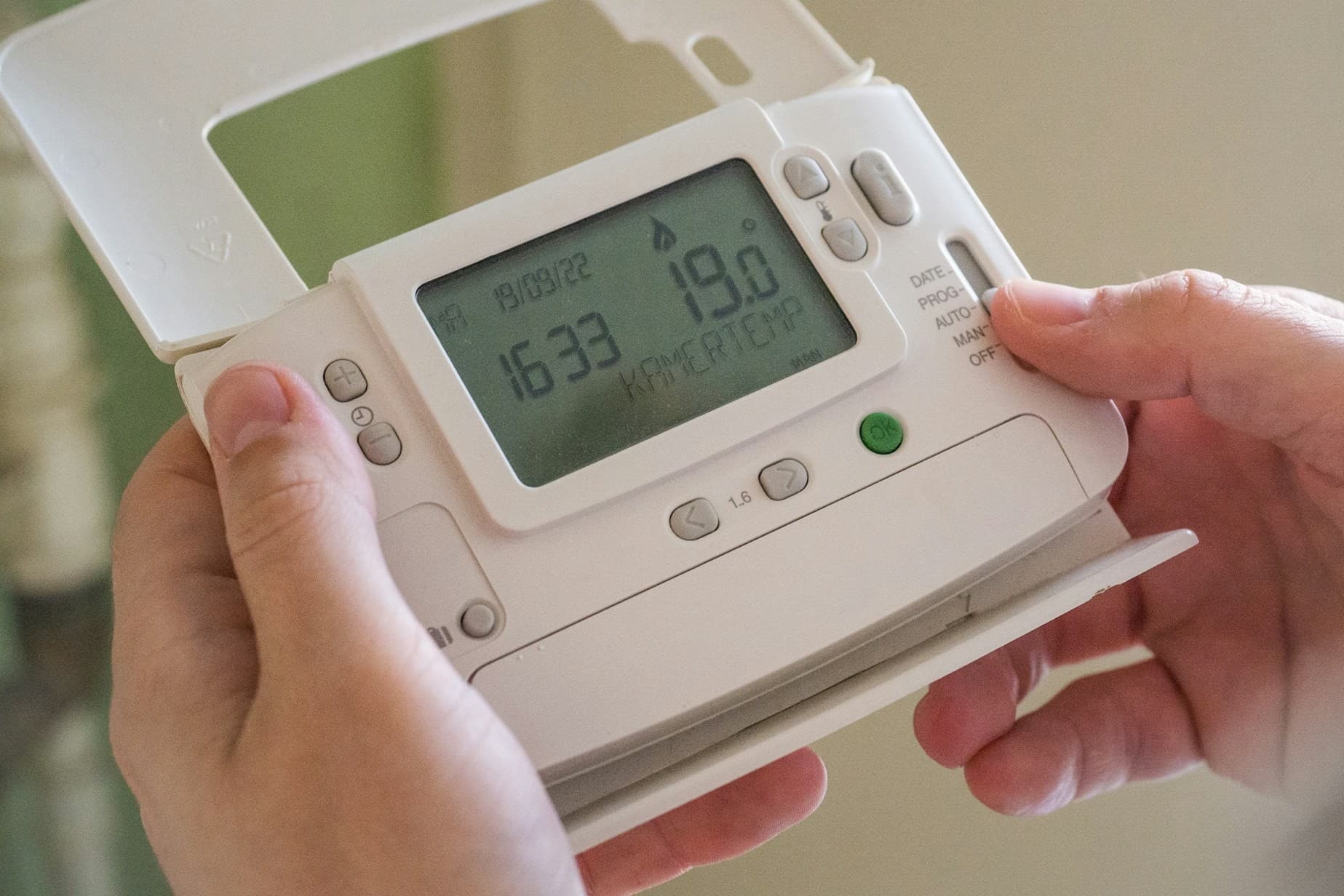 hands holding a thermostat. 
