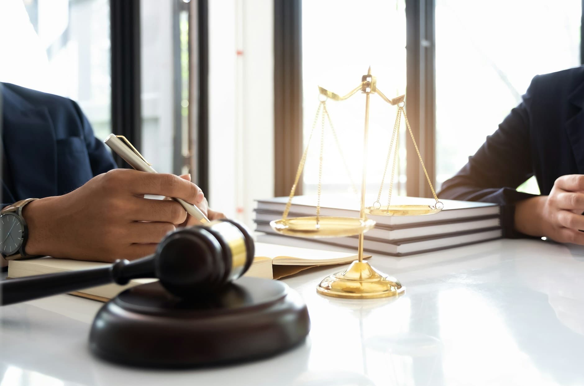 Image of a gavel and legal professionals at a desk. 