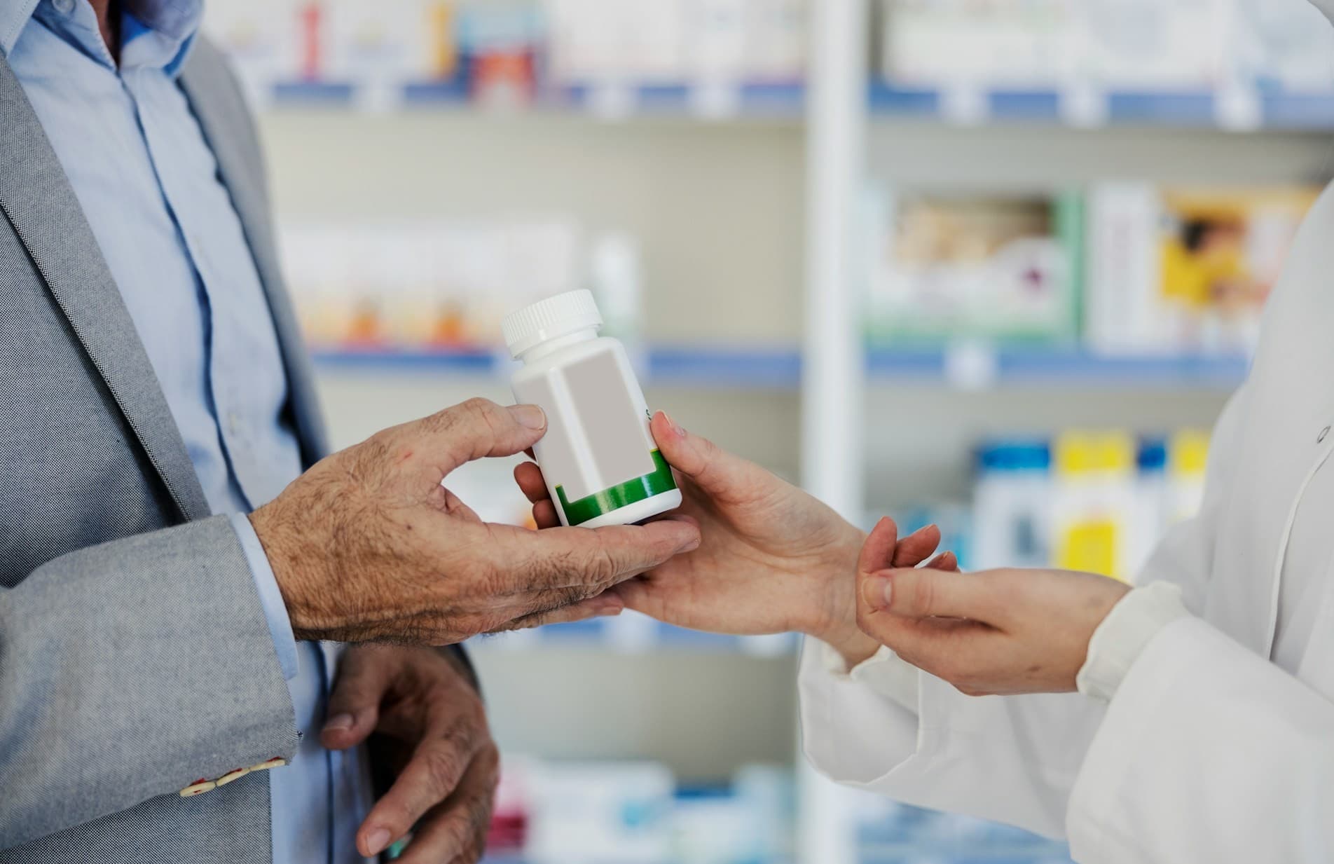 A pharmacist handing a customer prescription medication.