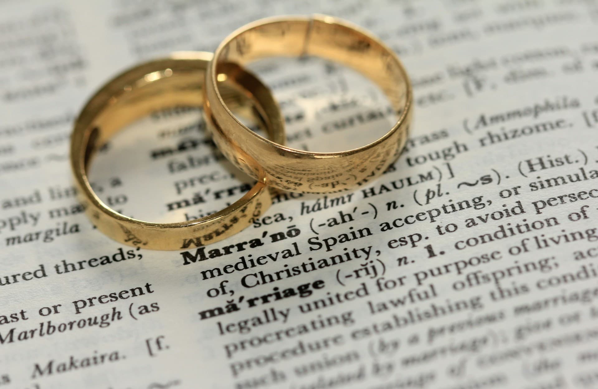 Two wedding rings on a dictionary opened to the definition of marriage.